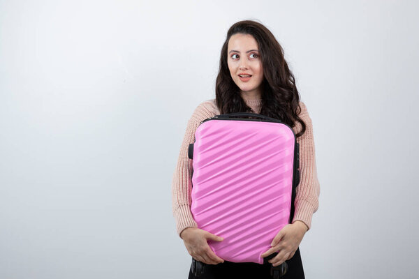 Студийный портрет красивой молодой женщины с розовым чемоданом. Высокое качество фото