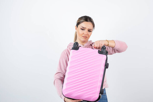 Фото красивой женщины с розовым чемоданом, стоящим над белым. Высокое качество фото