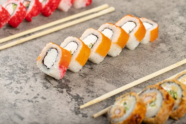 Taştan arka planda taze balıklı çeşitli suşi ruloları. Yüksek kalite fotoğraf