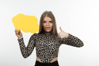 Sarı konuşma baloncuğu olan genç bir kadının portresi baş parmağını gösteriyor. Yüksek kalite fotoğraf