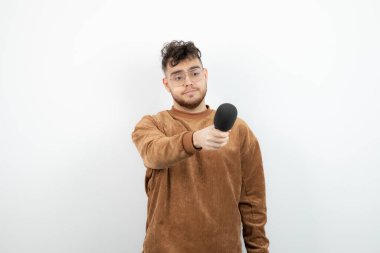 Beyazın üzerinde mikrofon tutan yakışıklı bir adamın portresi. Yüksek kalite fotoğraf