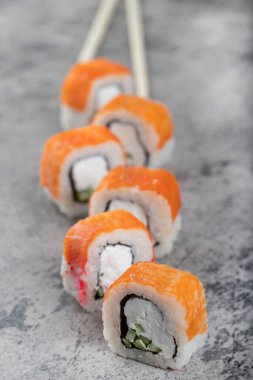 Somonlu suşi, füme yılan balığı, avokado, krem peynir ve tek kullanımlık ahşap çubuklar. Yüksek kalite fotoğraf