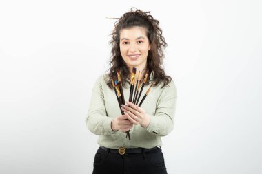 Elinde fırça tutan ve ayakta duran gülümseyen genç bir kız ressamın resmi. Yüksek kalite fotoğraf