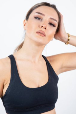 Siyah spor elbiseli sarışın kadın beyaz bir duvarın üzerinde dikilip poz veriyor. Yüksek kalite fotoğraf