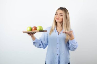 Tahtada yeşil ve kırmızı elmalar tutan sarışın bir kızın portresi. Yüksek kalite fotoğraf