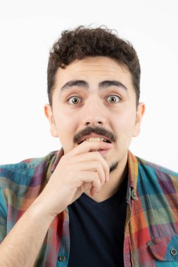 Kareli tişört giymiş ve beyaz duvarın üzerinde duran yakışıklı bir adam resmi. Yüksek kalite fotoğraf