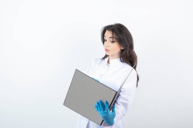 Esmer doktorun beyaz duvardan hasta kayıtlarını okuduğu fotoğraf. Yüksek kalite fotoğraf