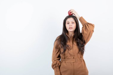 Kafasında kırmızı elma tutan esmer bir kız resmi. Yüksek kalite fotoğraf