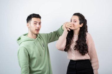 Esmer adam genç kadın mankene elleriyle ağzını kapatıyor. Yüksek kalite fotoğraf