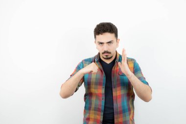 Kareli tişört giymiş ve beyaz duvarın üzerinde duran yakışıklı bir adam resmi. Yüksek kalite fotoğraf