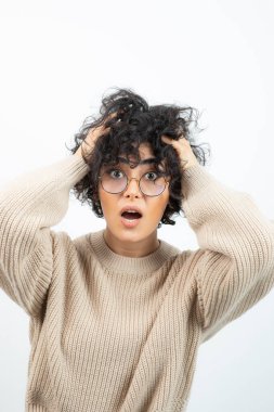 Gözlüklü, saçlarını tutan güzel kıvırcık bir kadın resmi. Yüksek kalite fotoğraf