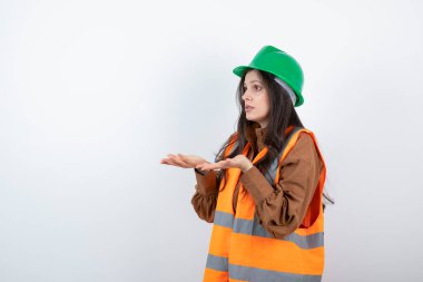 Turuncu yelekli kadın mühendis ve açık avuç içlerini gösteren yeşil başlıklı. Yüksek kalite fotoğraf