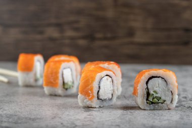 Somonlu suşi, füme yılan balığı, avokado, krem peynir ve tek kullanımlık ahşap çubuklar. Yüksek kalite fotoğraf