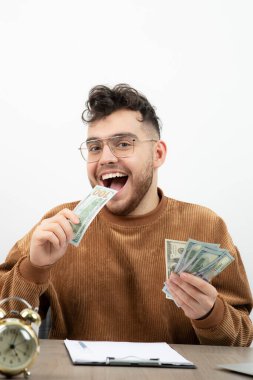 Genç ve mutlu muhasebeci masasında oturup paraları sayıyor. Yüksek kalite fotoğraf