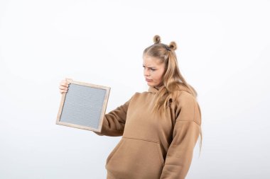 Boş bir çerçeveyle duran ve poz veren genç bir kızın portresi. Yüksek kalite fotoğraf