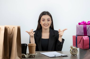 İş yerinde elinde hediyelerle oturan iş kadınının portresi.