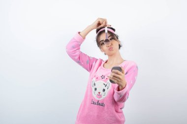 Pembe pijamalı genç bir kadın aynaya bakarken pudra sürüyor. Yüksek kalite fotoğraf