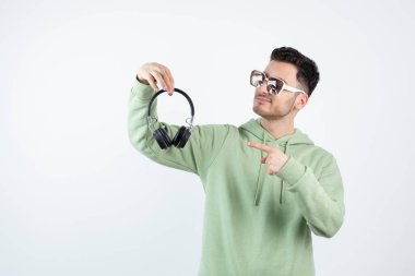 Gözlüklü yakışıklı bir adam kulaklığı işaret ediyor. Yüksek kalite fotoğraf