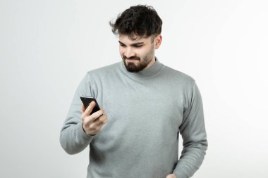 Akıllı telefonu beyaz duvara dayayan çekici adamın portresi. Yüksek kalite fotoğraf