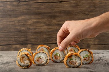 Taştan bir masanın üzerine yerleştirilmiş suşi rulosunu alan bir erkek. Yüksek kalite fotoğraf
