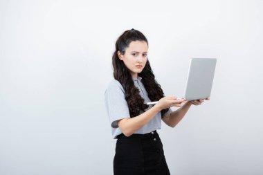 Beyaz arka planda dizüstü bilgisayarı tutan esmer bir kızın portresi. Yüksek kalite fotoğraf