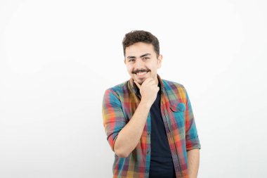 Kareli tişört giymiş ve beyaz duvarın üzerinde duran yakışıklı bir adam resmi. Yüksek kalite fotoğraf