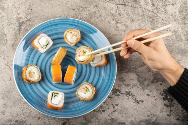 Taştan arka planda yemek çubukları olan suşi rulosunu ele alalım. Yüksek kalite fotoğraf