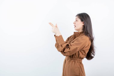 Beyaz duvara parmak doğrultan sevimli bir kadın modeli. Yüksek kalite fotoğraf