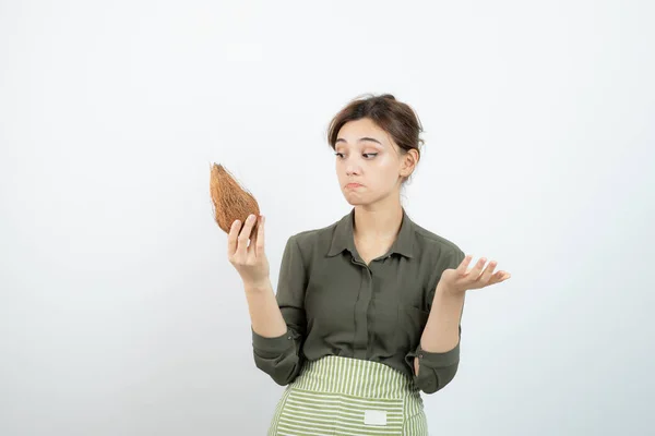 Imagem Uma Jovem Mulher Avental Segurando Coco Contra Parede Branca — Fotografia de Stock