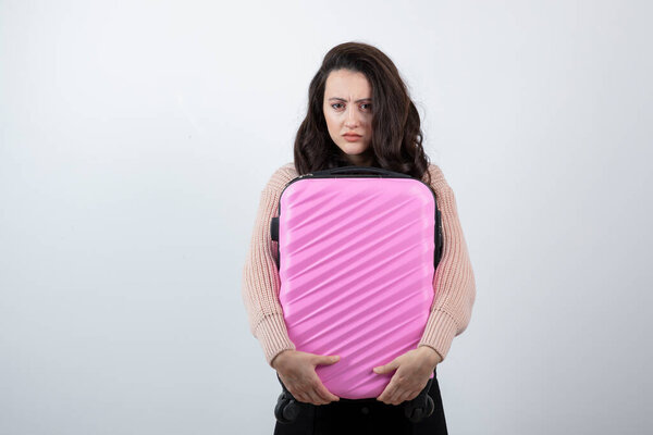 Студийный портрет красивой молодой женщины с розовым чемоданом. Высокое качество фото