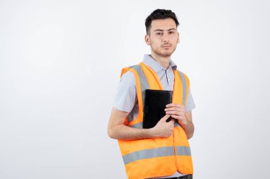 Yelek giymiş, elinde not defteri olan bir inşaat işçisinin fotoğrafı. Yüksek kalite fotoğraf