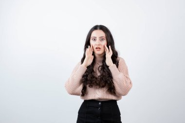 Güzel bir kadının el ele tutuşup kalçalarını beyaz duvara dayadığı görüntüler. Yüksek kalite fotoğraf