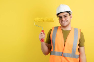 Miğferli genç işçinin resim rulosu tutarken fotoğrafı. Yüksek kalite fotoğraf