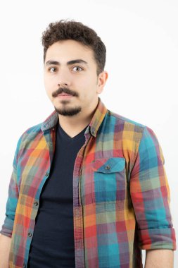 Kareli tişört giymiş ve beyaz duvarın üzerinde duran yakışıklı bir adam resmi. Yüksek kalite fotoğraf