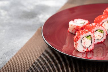 Kaliforniya suşisinin kırmızı tabağı mermer yüzeyde yuvarlanıyor. Yüksek kalite fotoğraf