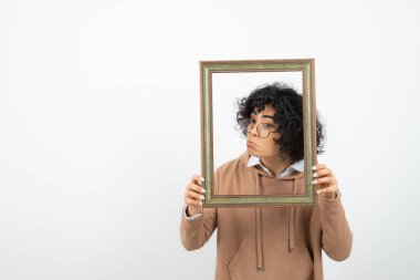 Kıvırcık esmer, komik bir kadın. Boş resim çerçevesiyle poz veriyor.