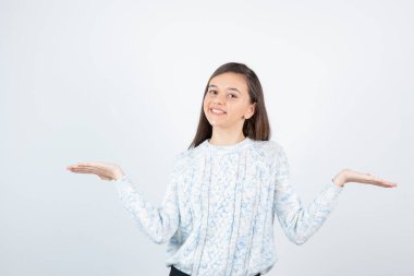 Beyaz arka planda duran süveter giyen kız