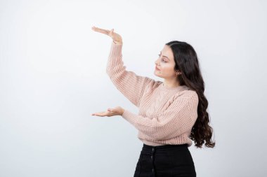 Güzel bir kadının bembeyaz duvara karşı duran ve boyunu gösteren görüntüsü. Yüksek kalite fotoğraf