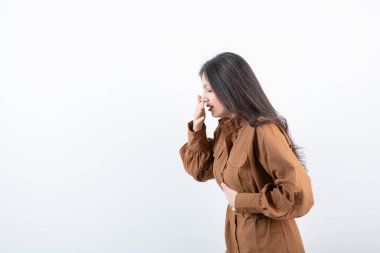 Güzel bir kadın mankenin el ele tutuşup beyaz duvara doğru öksürmesi. Yüksek kalite fotoğraf