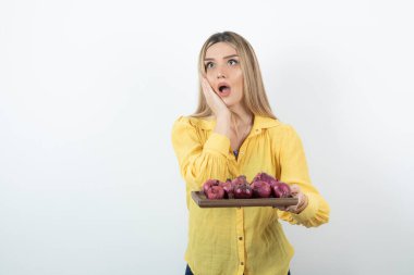 Güzel bir kızın portresi kırmızı soğan tutuyor ve bakıyor. Yüksek kalite fotoğraf