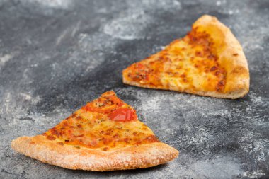 Taş zemine yerleştirilmiş iki dilim lezzetli peynirli pizza. Yüksek kalite fotoğraf