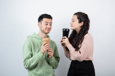 Birkaç genç arkadaş ellerinde kahve fincanlarıyla beyaz duvarda dikiliyorlar. Yüksek kalite fotoğraf