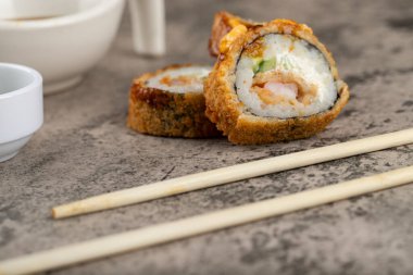 Taş bir masaya salatalık ve pilav konmuş lezzetli suşi ruloları. Yüksek kalite fotoğraf