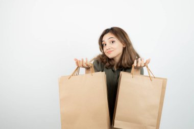 Beyazların üzerinde duran el işi çantaları olan genç bir manken resmi. Yüksek kalite fotoğraf