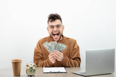 Genç ve mutlu muhasebeci masasında oturup paraları sayıyor. Yüksek kalite fotoğraf