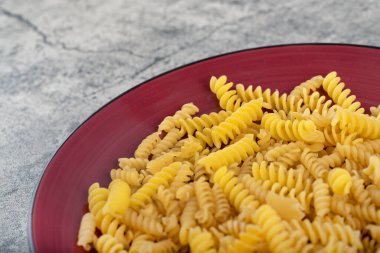 Taş masada kırmızı çiğ fusilli makarna. Yüksek kalite fotoğraf
