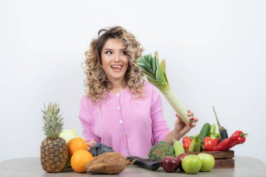 Masada çeşitli meyve ve sebzelerle poz veren güzel bir kadın.