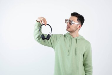 Gözlüklü yakışıklı bir adam kulaklığa bakıyor. Yüksek kalite fotoğraf