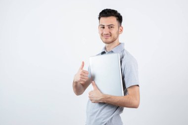 Beyaz duvarın üzerinde dizüstü bilgisayarı olan genç bir öğrencinin portresi. Yüksek kalite fotoğraf