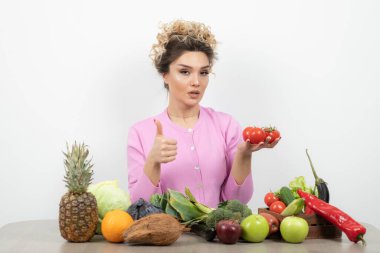 Masada çeşitli meyve ve sebzelerle poz veren güzel bir kadın.